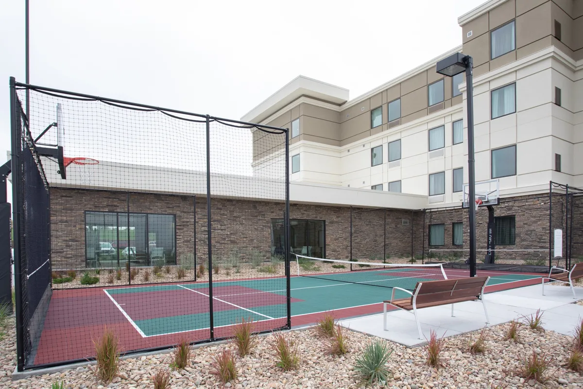 An exterior view of a basketball court and benches in front of the hotel facade, inviting guests to participate in friendly games or casual meet-ups. The open layout encourages team bonding and staying active in between meetings.