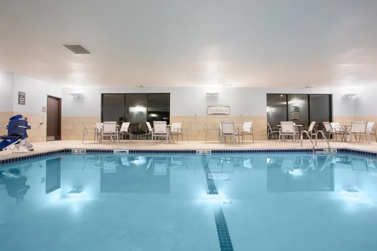 This image features a spacious indoor swimming pool area with comfortable seating and large windows that let in natural light. The pool is inviting and well-lit, suggesting a year-round recreational space perfect for families to unwind after a day of exploring local attractions.