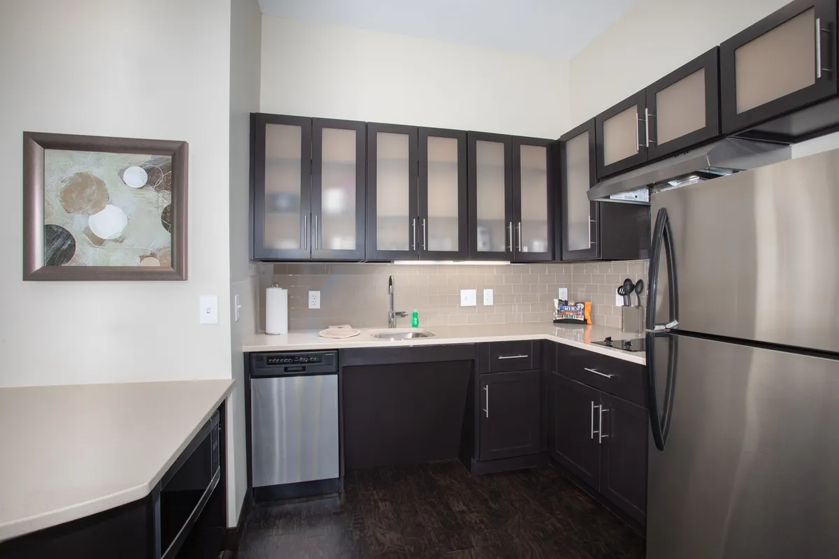 A stylish kitchen scene with modern cabinetry, stainless steel appliances, and a spacious countertop. The open layout is ideal for cooking, entertaining, and gathering, with artwork on the wall adding a homey touch.